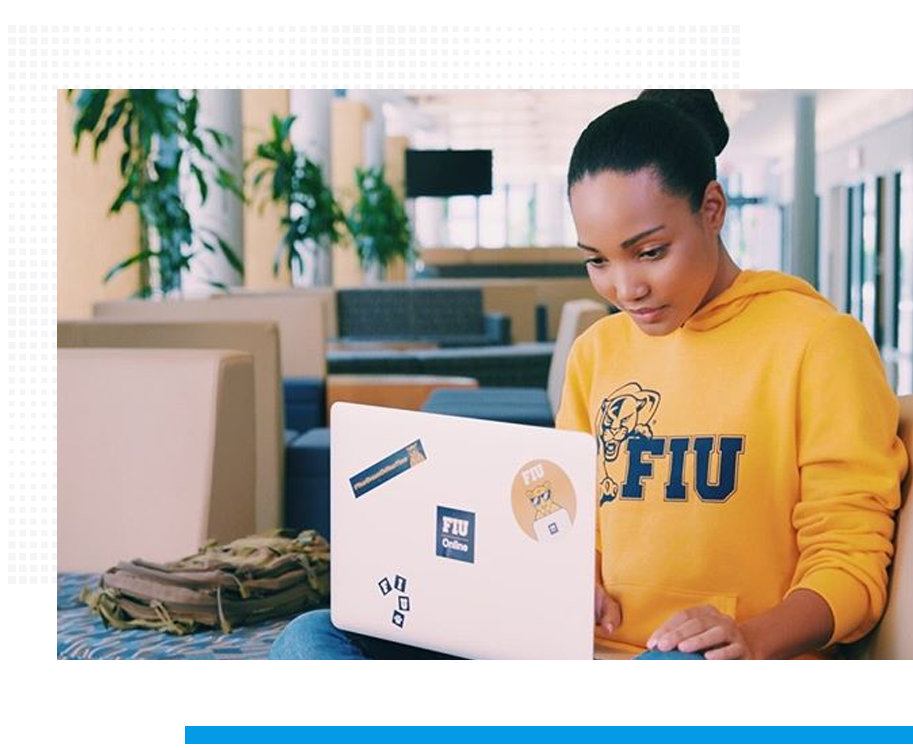 young woman with hair in a bun, wearing FIU sweatshirt, working on her laptop